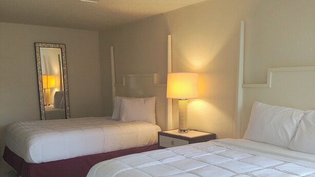 A hotel room with two beds, a nightstand with a lamp, a mirror, and a marble-patterned floor. - Super Inn Motel (Oklahoma City)