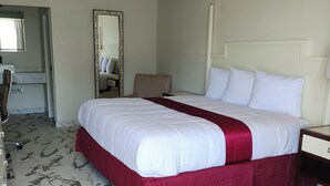 A hotel room with a large bed, a desk, a chair, a mirror, and a bathroom visible through an open door. - Super Inn Motel (Oklahoma City)