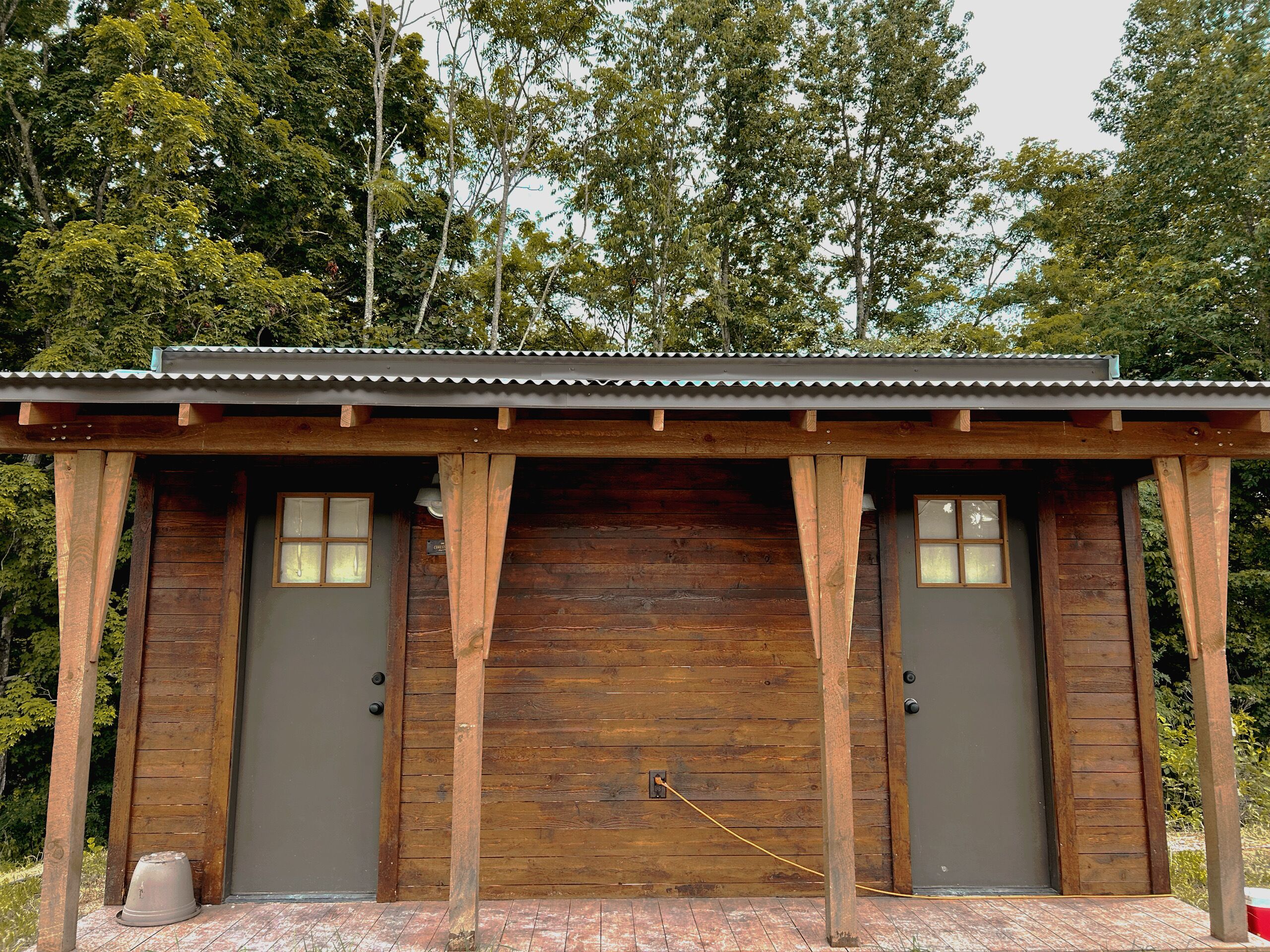 A wooden cabin with two doors, a metal roof, and a brick floor.