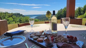 Ein Essplatz im Freien mit herrlichem Ausblick, einer Flasche Weißwein und verschiedenen Snacks.