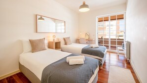 Habitación de hotel con dos camas, un escritorio, una silla, un ventanal y vistas al exterior.