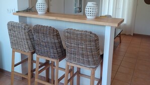 A kitchen with a wooden countertop, two wicker bar stools, and two white decorative vases.