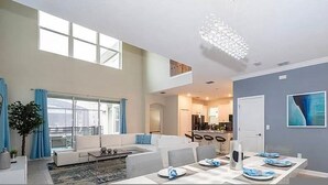 Un vaste espace de vie comprenant une table à manger pour quatre personnes, un canapé et une grande fenêtre.