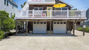 A two-story house with a balcony, a yellow umbrella, and two garage doors.
