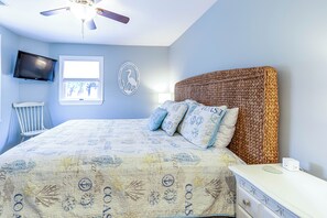 Un dormitorio con cama, televisor, ventana y ventilador de techo.