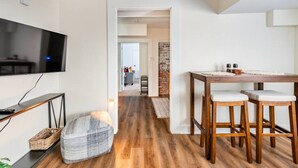 En moderne stue med fjernsyn, et træspisebord og et hyggeligt siddeområde.