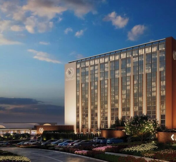 A modern building with a glass facade, a parking lot, and landscaped areas.