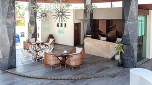 A lobby with a reception desk, seating area, and modern chandeliers. - 3 bedroom penthouse in Bucerias - Ocean view, BBQ and hotel-like amenities (Bucerías)