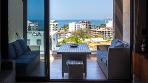 A balcony with a view of the sea, a table, and two sofas. - 3 bedroom penthouse in Bucerias - Ocean view, BBQ and hotel-like amenities (Bucerías)