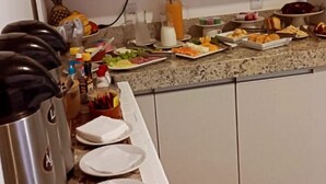 Une cuisine dotée d’un plan de travail en granit, de meubles blancs et d’une bouilloire en acier inoxydable.