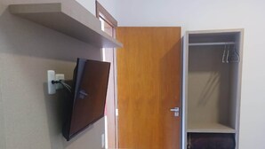 Une chambre dotée d’un téléviseur encastré, d’une porte en bois et d’une armoire avec des étagères.