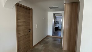 Ein Korridor mit einer Holztür links, einer Holztür rechts und einem gefliesten Boden.