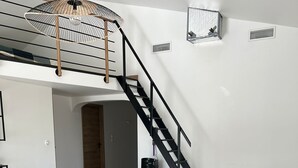 Ein Essbereich mit Holztisch und Stühlen, einer Treppe und einem Deckenventilator.