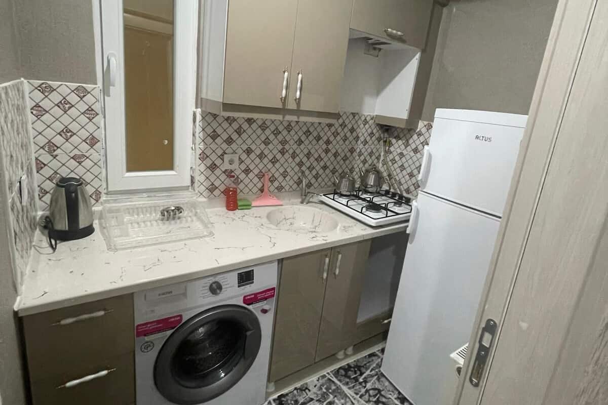 A compact kitchen with a washing machine, a gas stove, and a refrigerator.