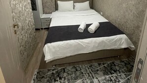 Ein Hotelzimmer mit einem Bett, einem Nachttisch, einem Kleiderschrank und einem gemusterten Boden.