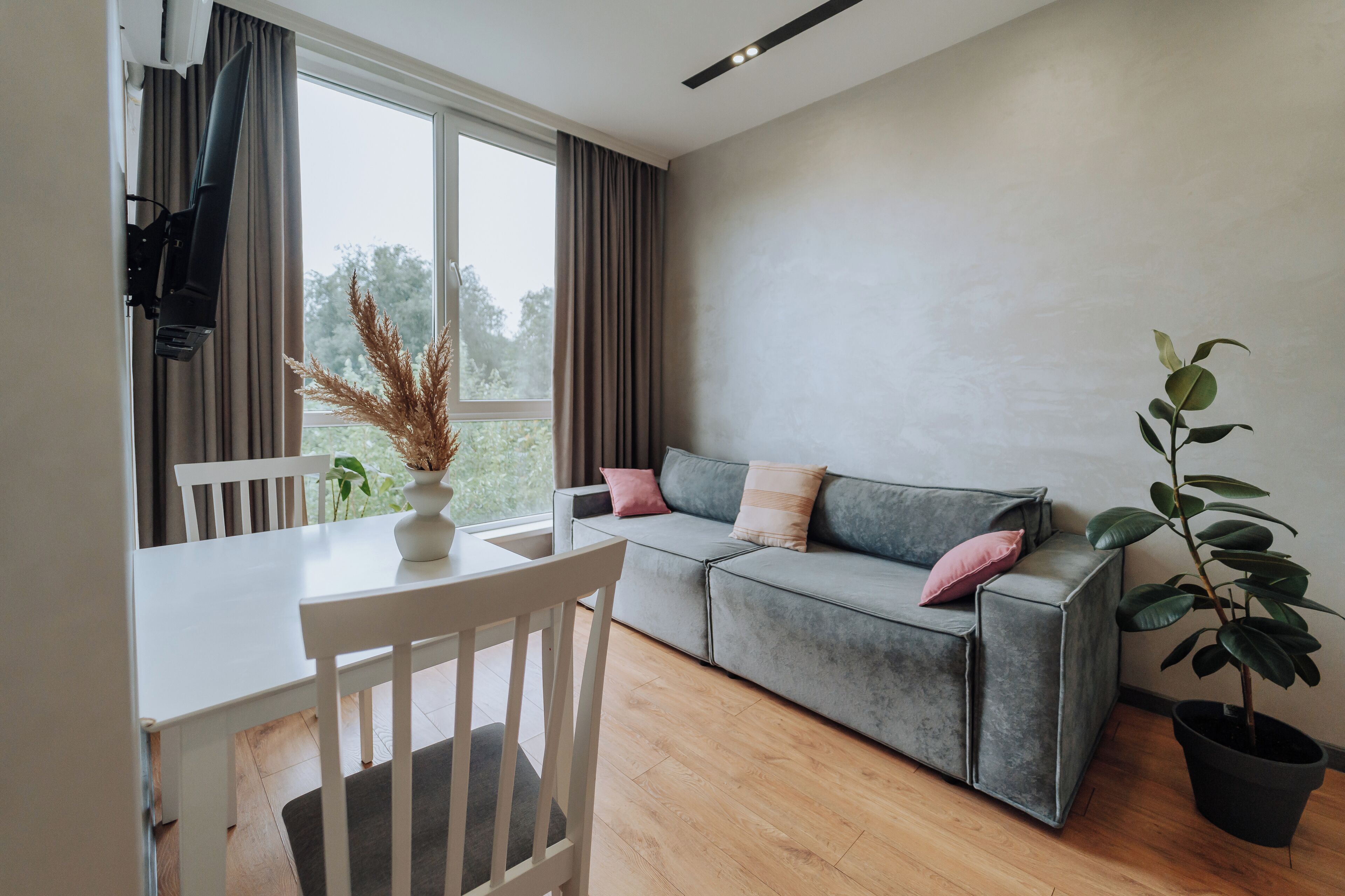 A modern living room with a grey sofa, white chair, and a dining table.