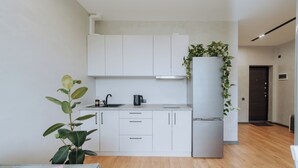 Eine moderne Küche mit weißen Schränken, einem Edelstahl-Kühlschrank und einem Blumentopf.