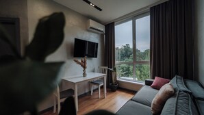 Ein modernes Wohnzimmer mit einer Couch, einem Esstisch mit Stühlen, einem Blumentopf und einem an der Wand befestigten Fernseher.