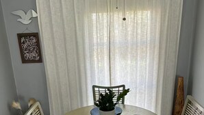 Ein Essbereich mit einem runden Tisch, vier Stühlen, einer Zimmerpflanze und einem dekorativen Willkommensschild.