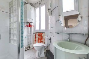 A bathroom with a toilet, sink, and shower area. - Comfort and tranquility near the Canal de l’Ourcq (Paris)