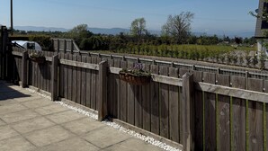 A wooden fence with a garden bed, a clear sky, and distant hills.