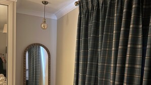 A bedroom with a bed, a mirror, a wardrobe, and a window with curtains.