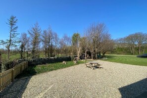 A gravel area with a picnic table and a wooden fence.