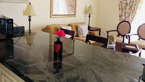 Ein Wohnzimmer mit einer Couch, einem Couchtisch mit einer Vase, einer Lampe und einem gerahmten Bild an der Wand.