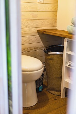 A wooden floor, a white toilet, and a trash can in a bathroom. - Tiny house with Nordic bath 10 minutes from the Baie de Somme (Saint-Blimont)