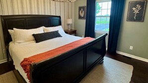 Een slaapkamer met een groot bed, een kroonluchter, gestreepte behang en uitzicht op de omgeving.