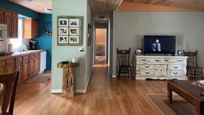 Een ruime woonkamer met houten vloeren, een televisie en een eethoek.