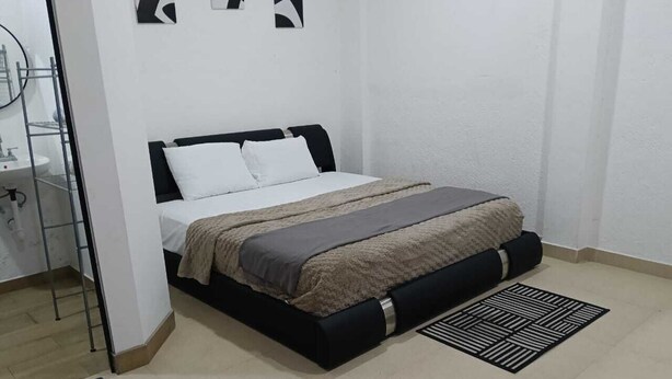 Un dormitorio con cama, mesita de noche, espejo y radiador.