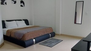 Un dormitorio minimalista con cama, una mesita y un espejo montado en la pared.