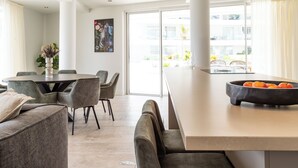Un comedor moderno con una mesa redonda, sillas tapizadas en gris y un ventanal con vistas a la ciudad.