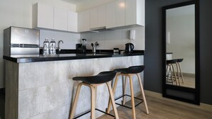 Una cocina moderna con una isla central, electrodomésticos de acero inoxidable y taburetes de madera.