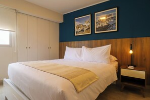 Une chambre à coucher avec un lit, une table de chevet, une tête de lit en bois et deux tableaux encadrés accrochés au mur.