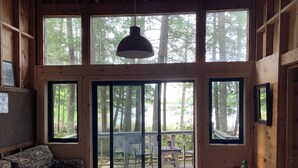 A cabin with large windows, a sofa, a table, and a hanging light fixture.