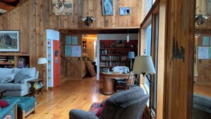 A wooden interior with a sofa, armchair, bookshelves, and framed pictures on the walls.