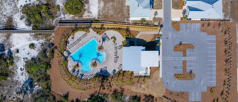 Vista aérea de un complejo turístico con piscina, aparcamiento y varias edificaciones de techos azules.