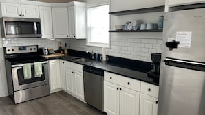 A modern kitchen with white cabinets, stainless steel appliances, and a black countertop.