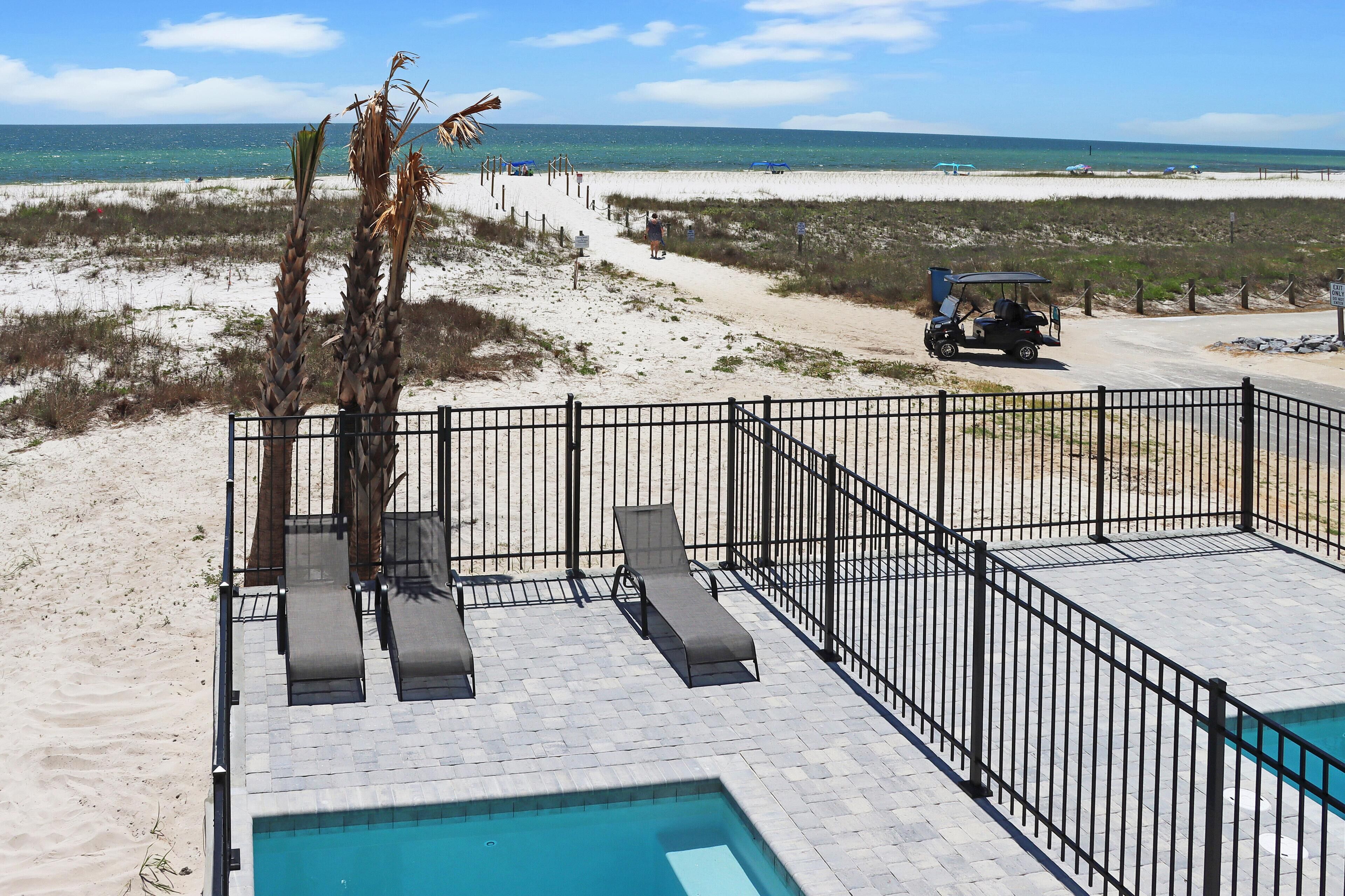 Ein Poolbereich mit Liegestühlen und Blick auf den Strand.