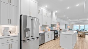 A modern kitchen with white cabinetry, stainless steel appliances, and a wooden floor. - Salty Sisters (Port St. Joe)