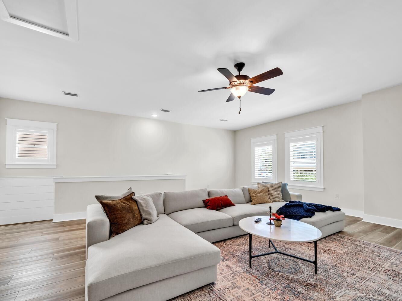 A modern living room with a sectional sofa, a coffee table, and a ceiling fan.
