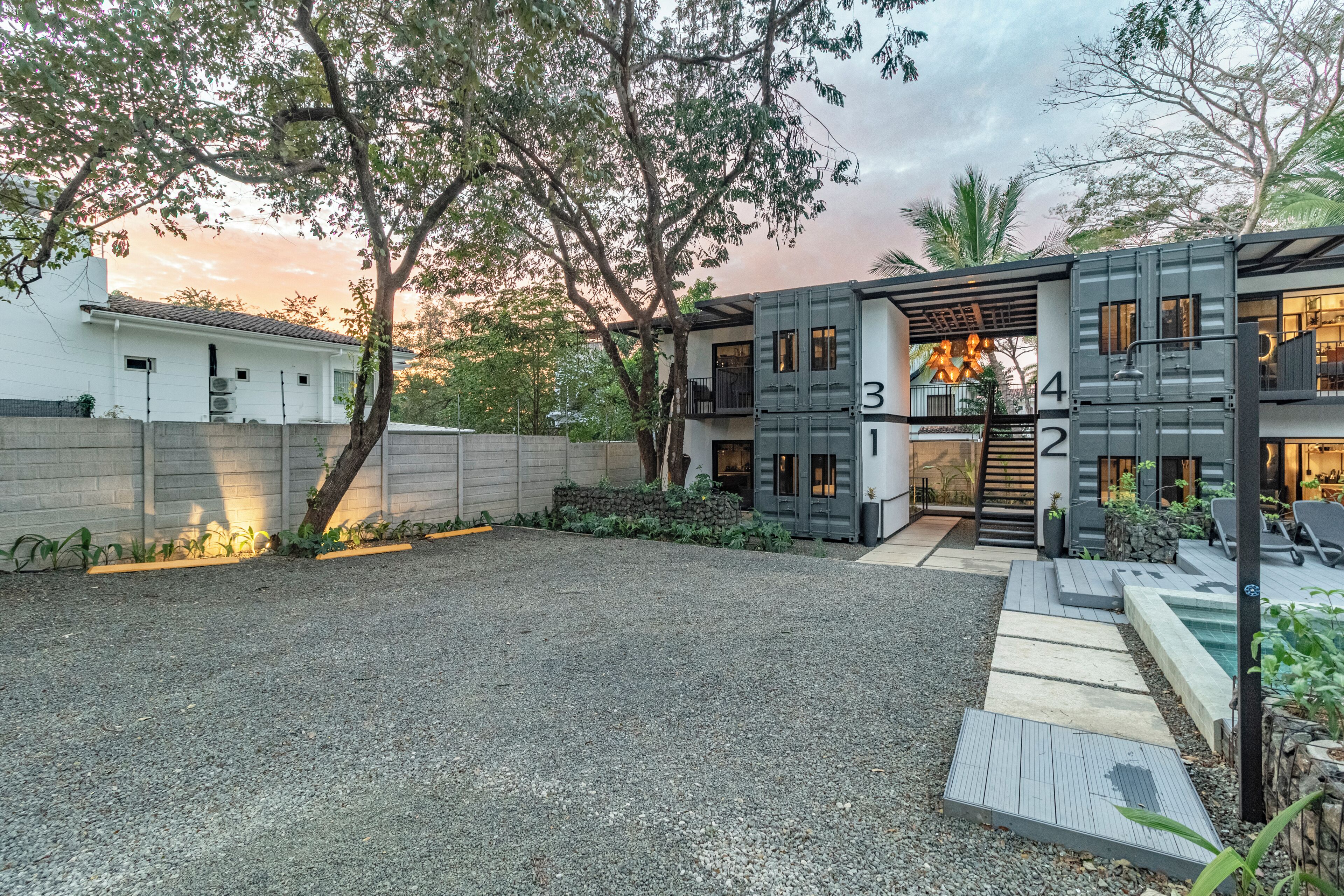 A modern two-story building with a gravel driveway and a small pool area.