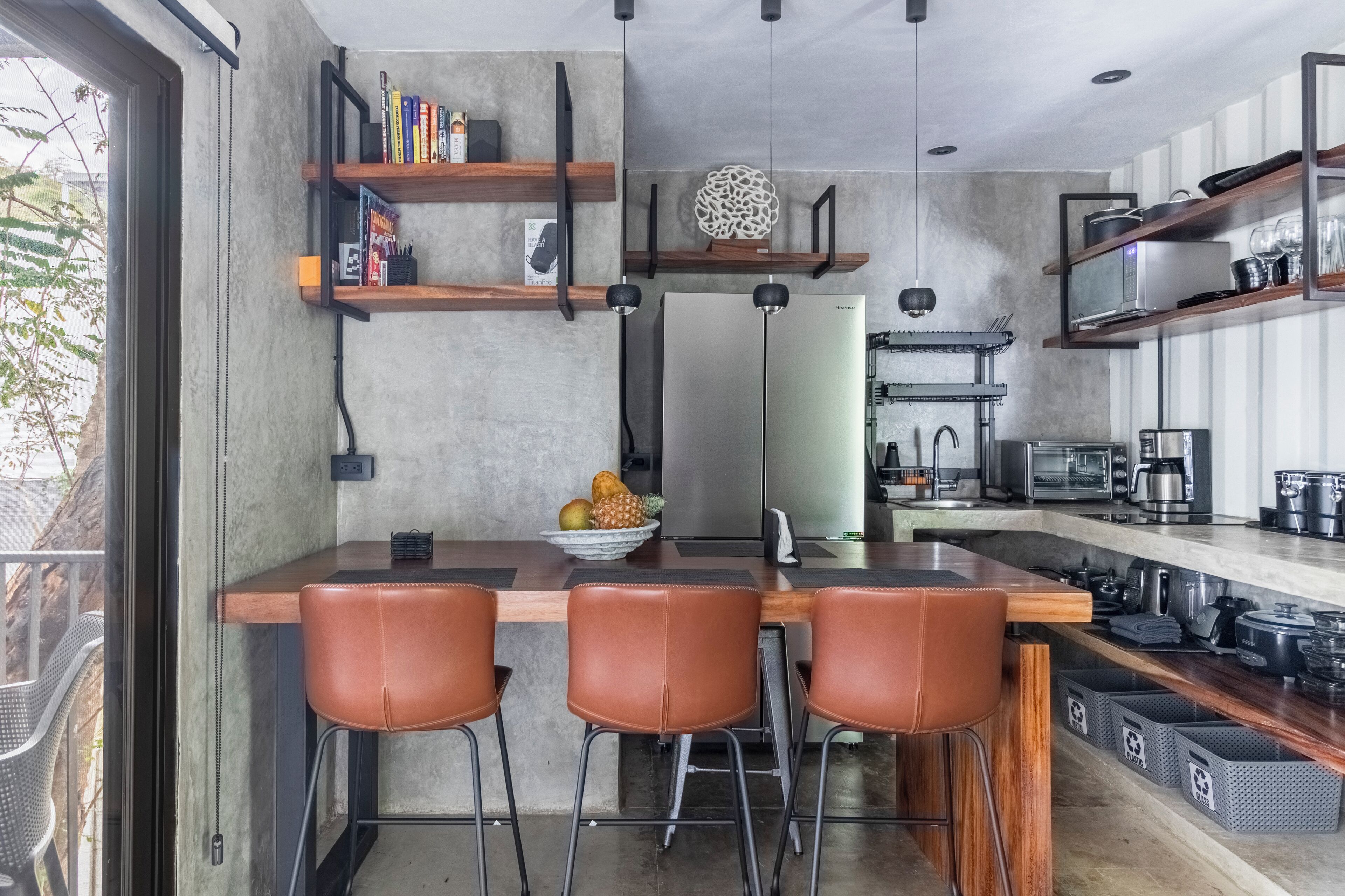 A modern kitchen with a central island, bar stools, and built-in shelves.