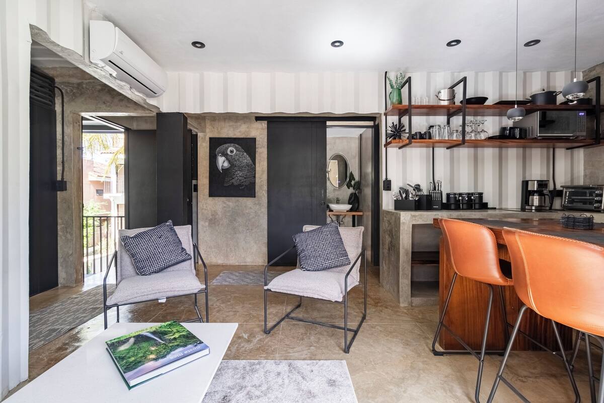 Een moderne keuken met een bar, twee stoelen en een eettafel.