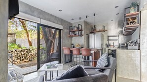 A modern kitchen with a dining area, built-in shelves, and a large sliding glass door leading to a patio. - Z102 studios (Potrero)