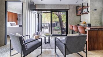 Una cocina moderna con encimera de madera, una zona de comedor con sillas tapizadas en gris y un amplio ventanal corredero que da a un patio exterior.