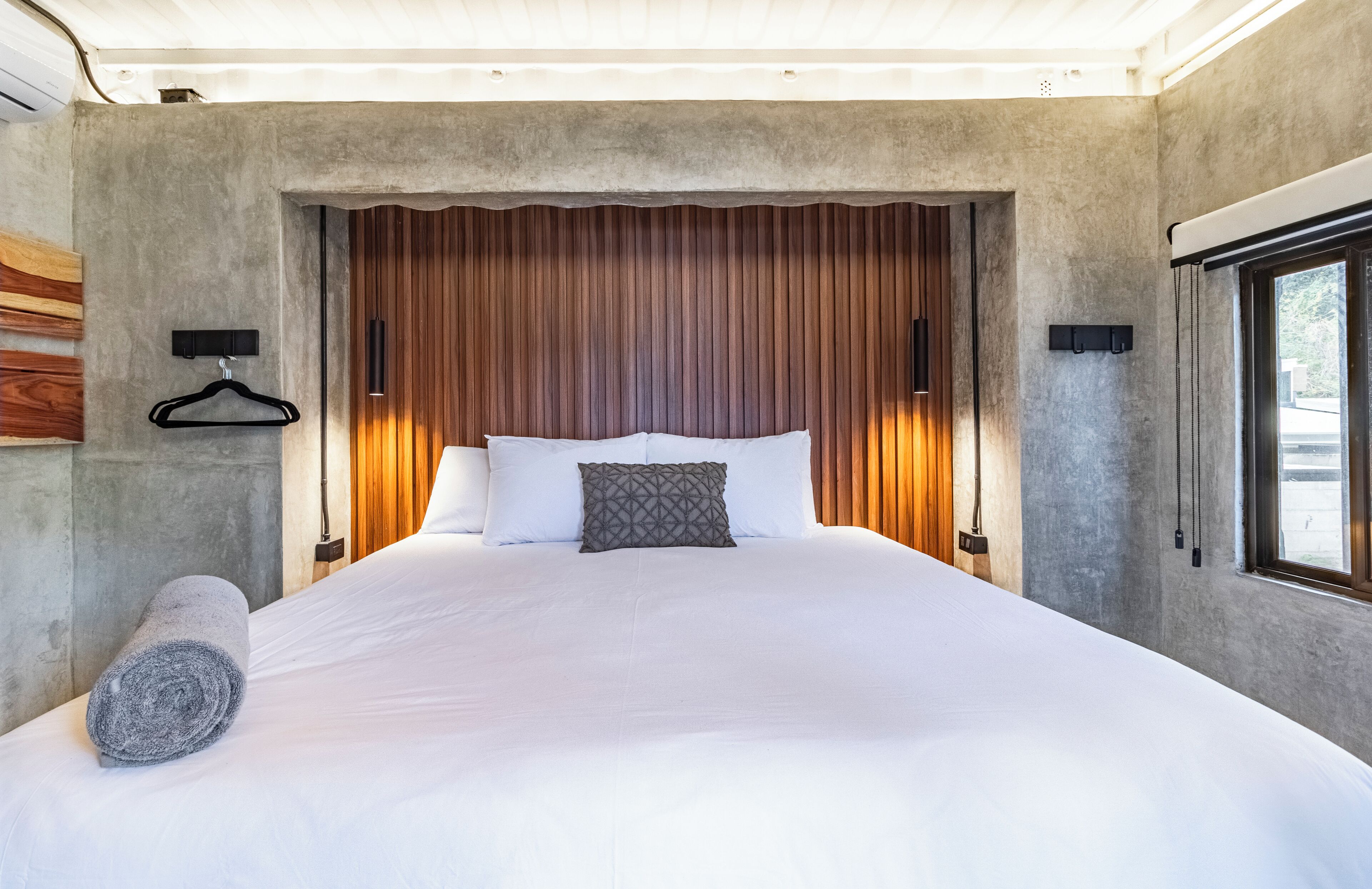 A large bed with white linens, a wooden headboard, and a hanging towel.