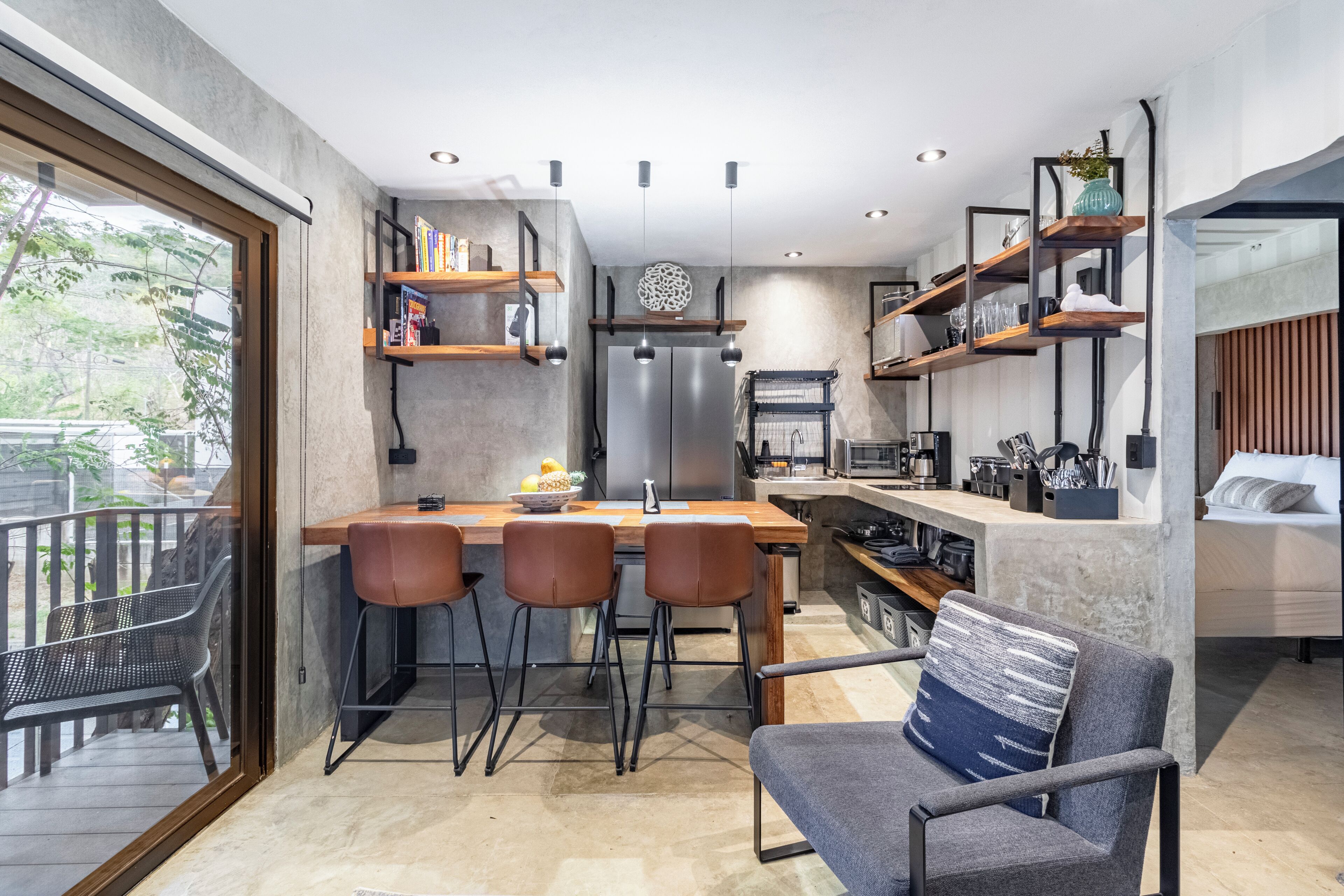Una cocina moderna con una isla central, taburetes de bar y estantes empotrados.